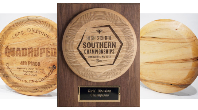 Three wood award trophies are shown. One is mounted on a plaque with a metal wording plate at the bottom. Two have been engraved with a design and wording, the other is blank.